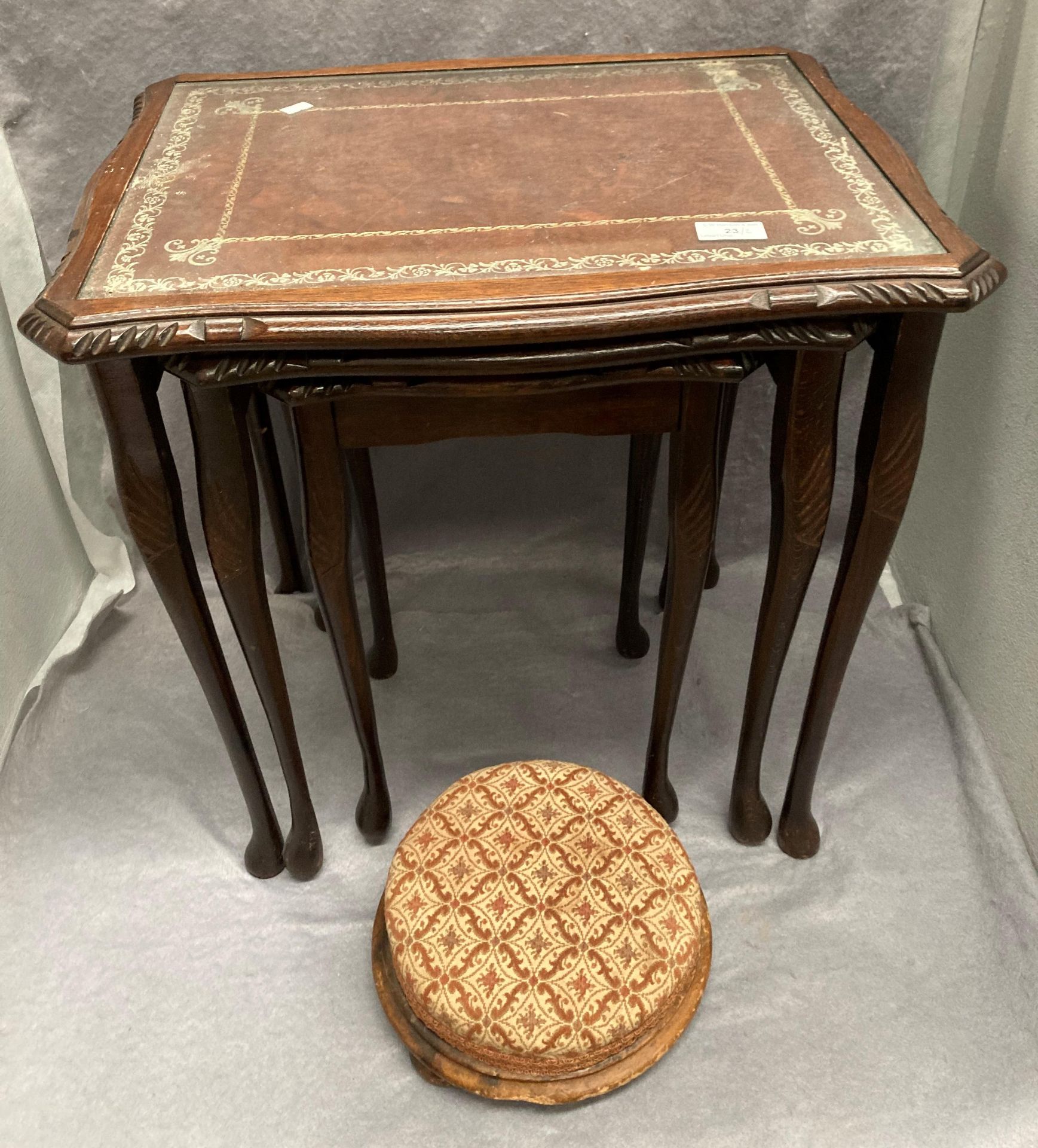 A nest of three coffee tables with brown tooled leather effect tops with inset glass and a small