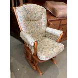 A Dutalier wood framed rocking armchair model 11490 with light brown floral patterned upholstery