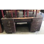 A distressed 1950s oak nine drawer twin pedestal desk,