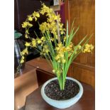 An artificial plant in ivory coloured planter