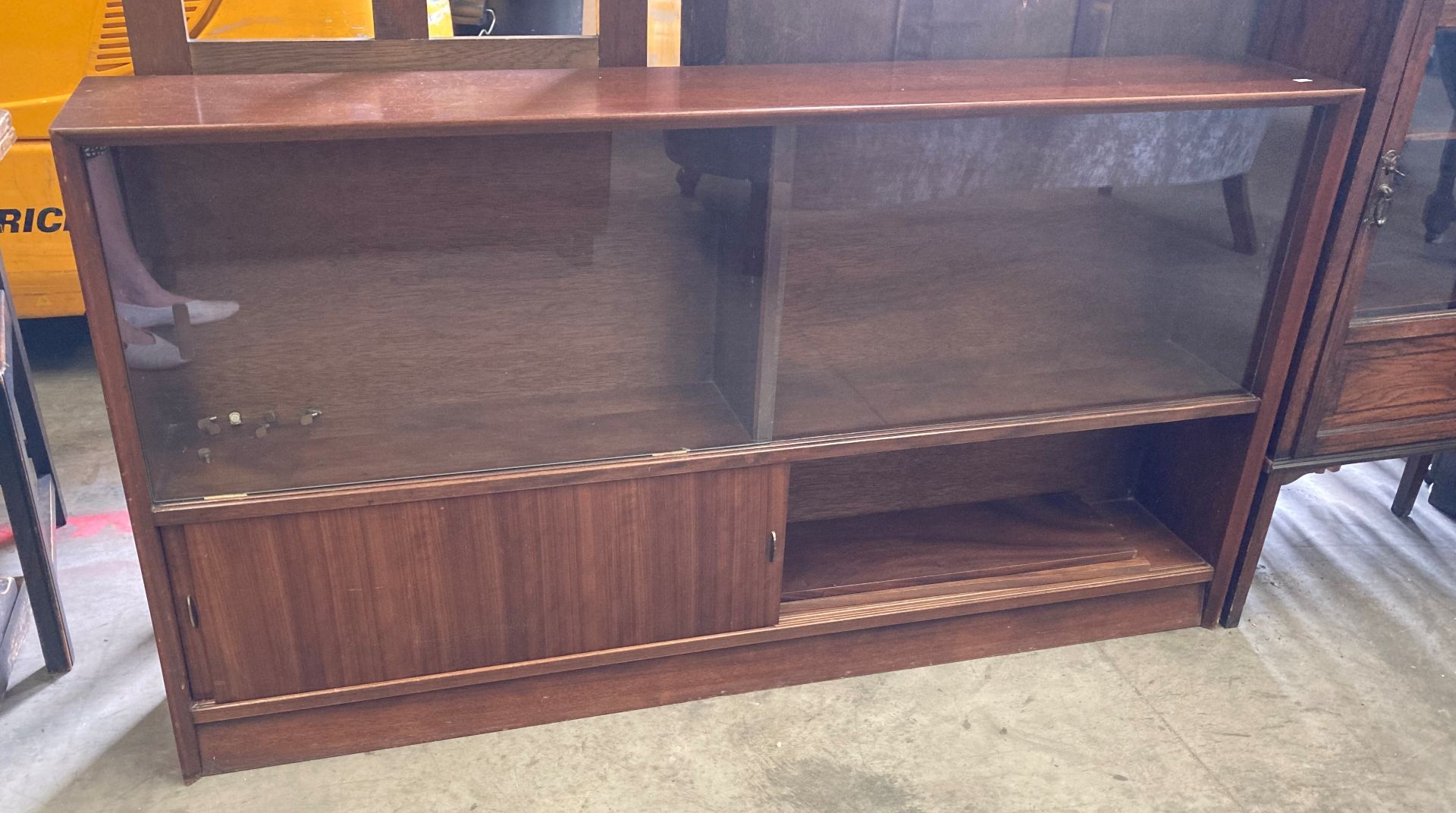 An oak finish low display cabinet with upper sliding glazed doors over two sliding doors by Herbert