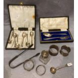 Silver sugar tongs, mustard spoon, four napkin rings, glass toilet bottle with silver top,