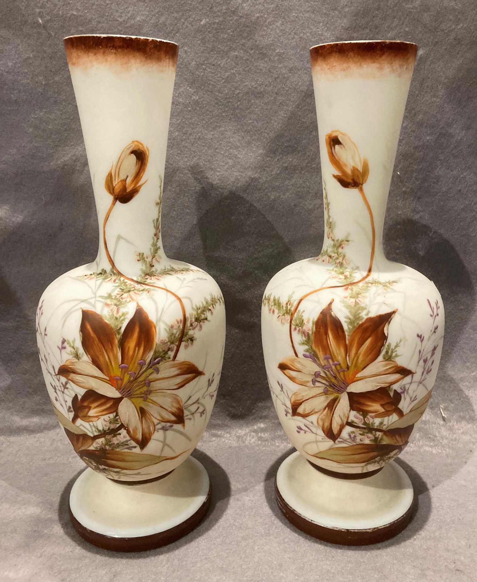 A pair of iridescent glass vases, painted with flowers,