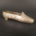 An antique Dutch silver oversized model of a slipper ornately embossed with floral and swag