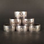 Six white metal napkin rings with engraved scenes including camels, boats etc,