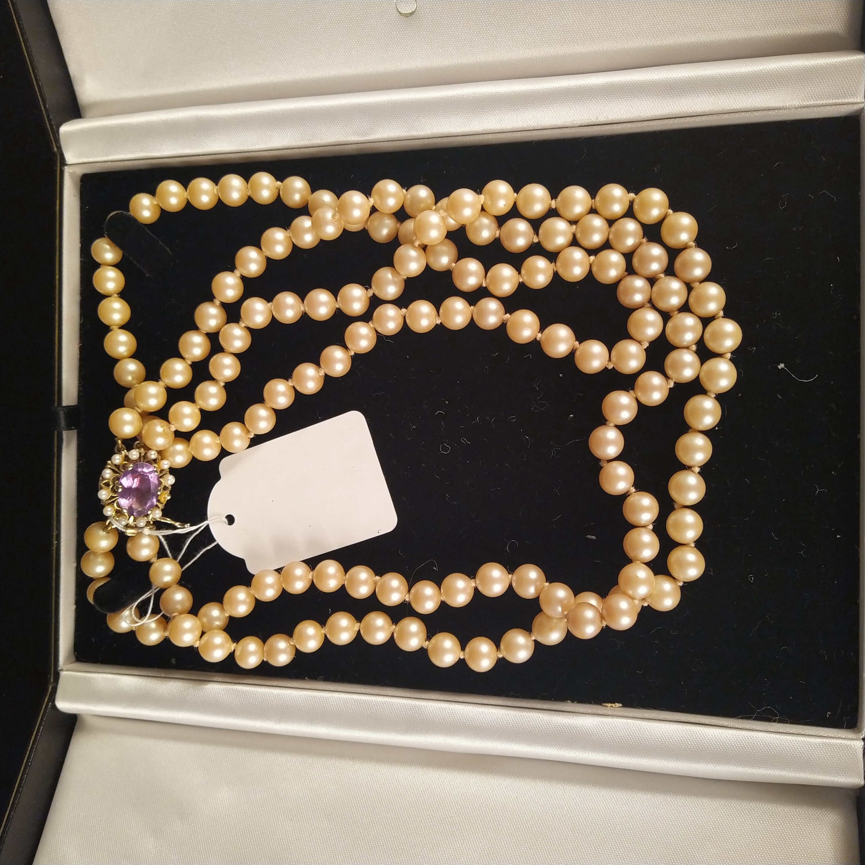 A triple strand simulated pearl necklace set with large 9ct gold amethyst and seed pearl clasp (one
