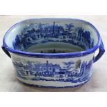 A large ceramic blue and white foot bath decorated with a town scene,