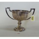 A Chinese white metal twin handled trophy cup with floral decoration,