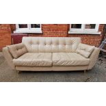 A DFS cream leather three seater sofa on turned legs and coloured buttoned back detail