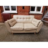 A DFS cream leather two seater sofa on turned legs and coloured buttoned back detail