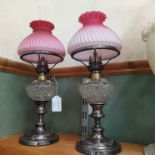 A pair of oil lamps on plated stands,