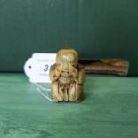 An antique detailed carved ivory netsuke of a seated figure of a boy pulling a face, unsigned,