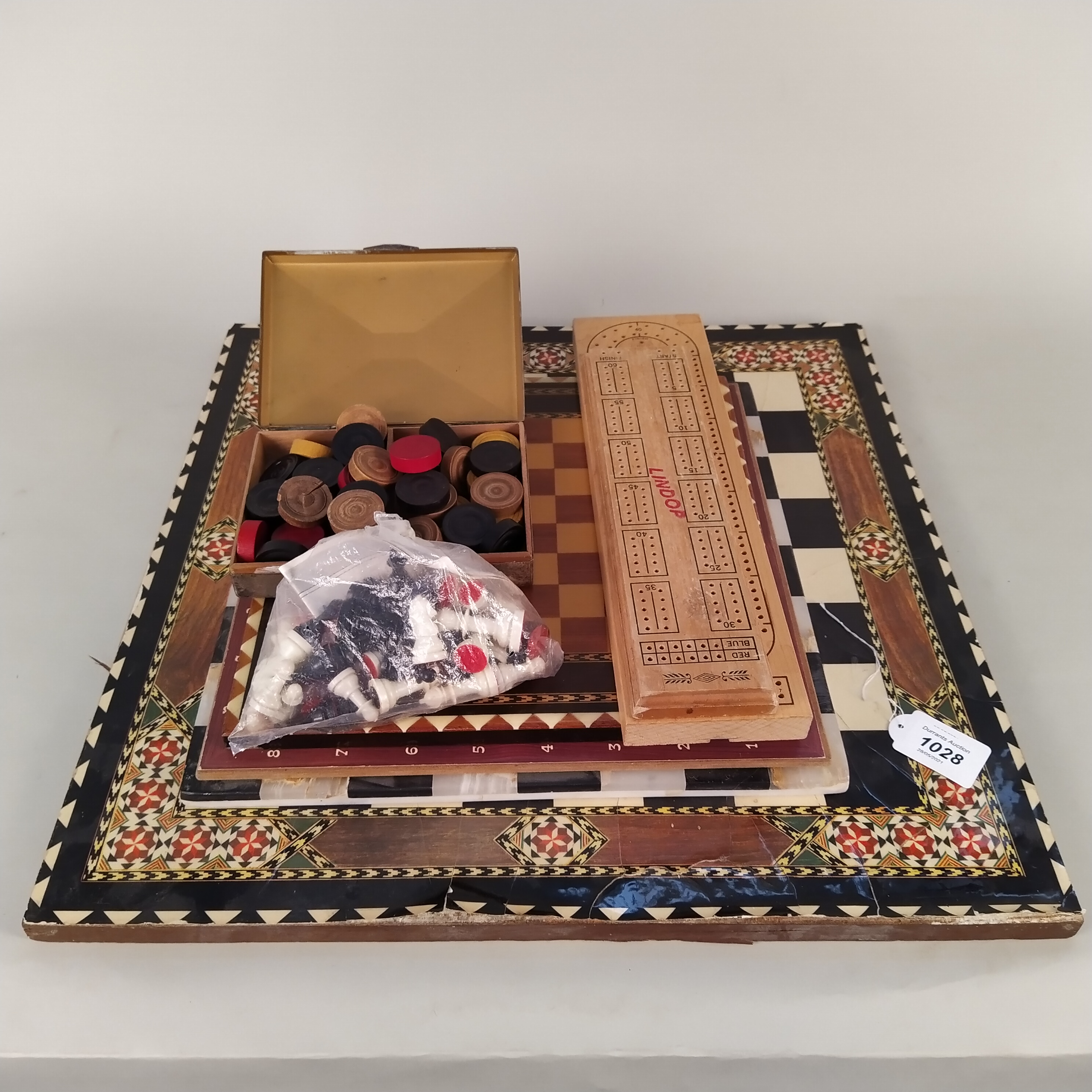 A hardstone chess board together the three light wood examples, two wooden cribbage boards,