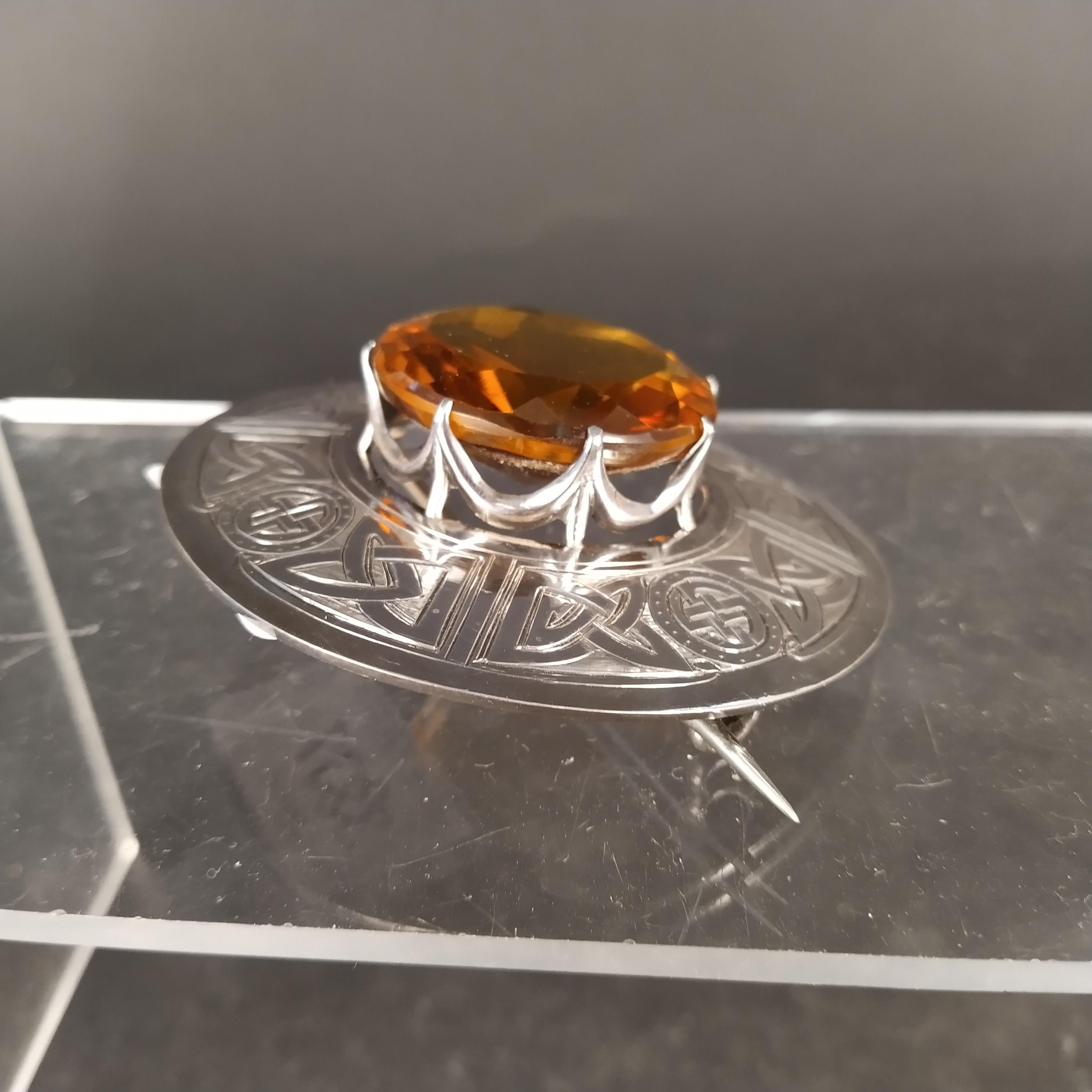 A Scottish silver plaid brooch with engraved Celtic design surrounding a large central orange stone, - Image 2 of 3