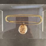 An unmarked yellow metal necklace and foliate engraved locket,