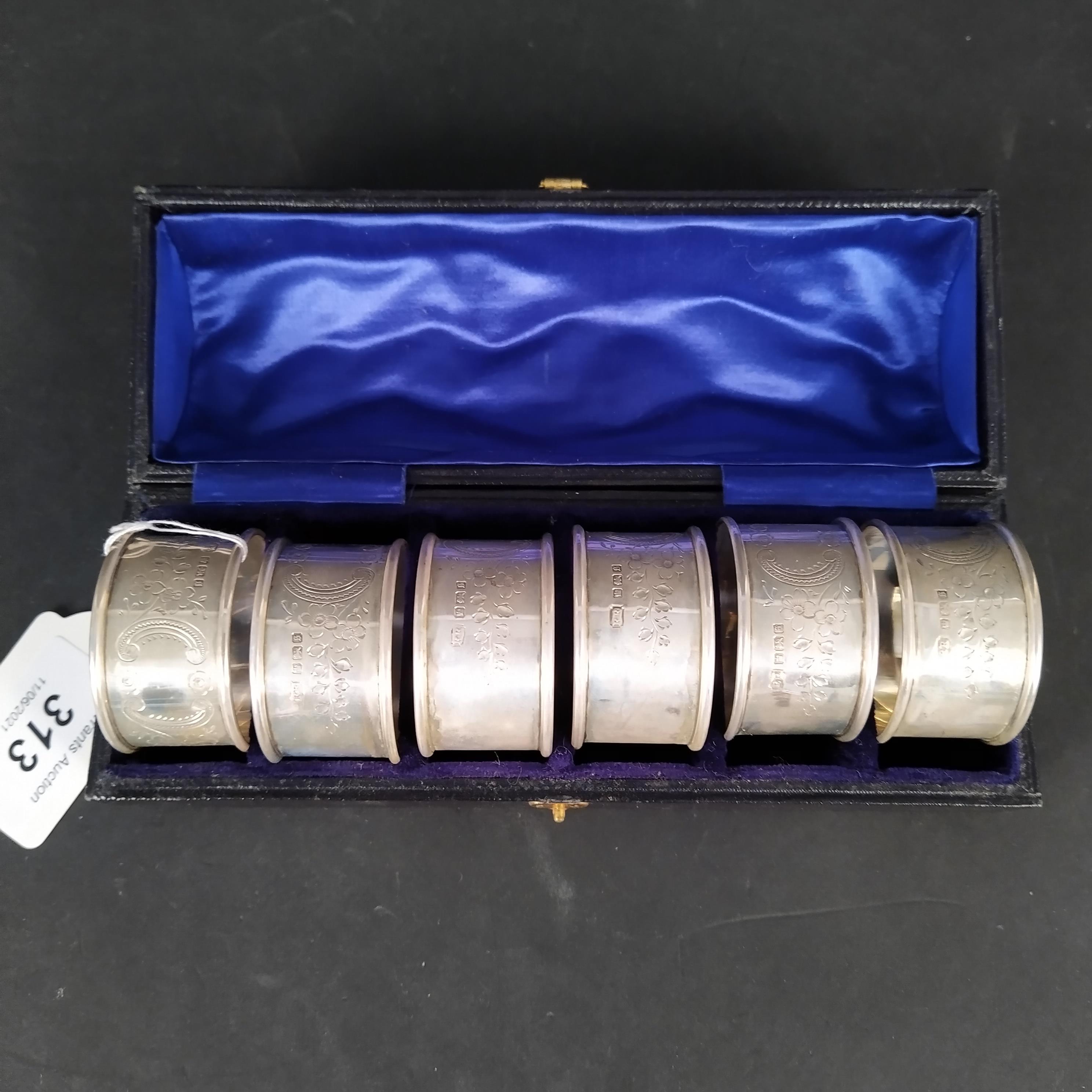 A cased set of six silver napkin rings with engraved foliate decoration,