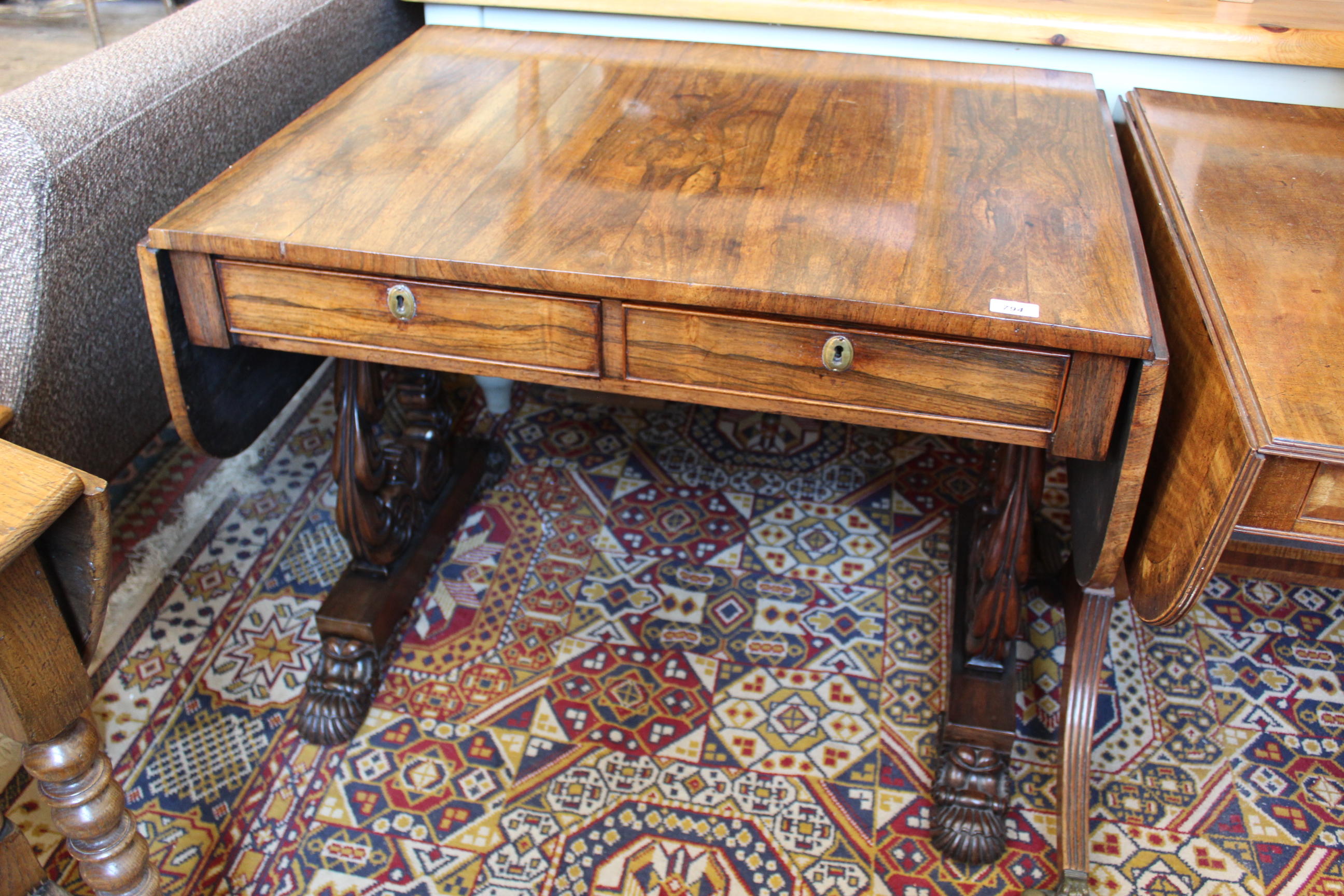 A George IV rosewood sofa table with carved shaped end supports on bold carved paw feet and inset