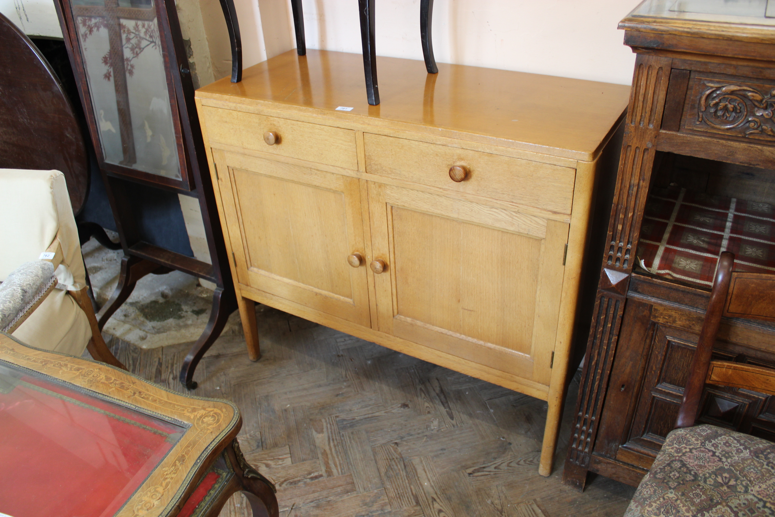 A vintage Remploy light oak two drawer two door cupboard on legs