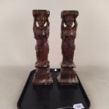 A pair of possibly 18th Century carved wood candle stands of female form,