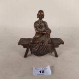 An Asian bronze figure of a Buddha seated on a low table