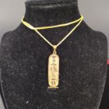 An Egyptian gold hieroglyph pendant on an 18ct gold box link chain (stamped 750),