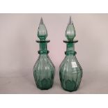 A pair of hand blown and cut green decanters (some chips to neck and an old repair to stoppers)