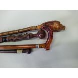 Four walking sticks including a carved eagle signed 'M S 99' plus a 19th Century rosewood metal