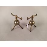 A pair of Arts and Crafts Christopher Dresser design globular brass fire dogs on tripod feet