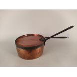 A large 19th Century seamed copper saucepan and lid with iron handles,