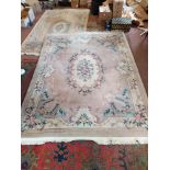A Chinese wool carpet with central floral panel, floral borders on a pink ground,