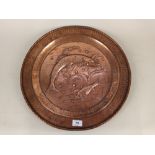 An Arts and Crafts copper charger with embossed fish decoration