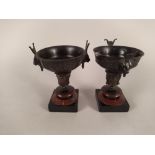 A pair of late 19th Century French bronze miniature urns on black and rouge marble square bases