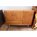 A mid Century Ercol blonde teak sideboard with a combination of three cupboards and a single drawer