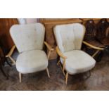A pair of mid Century blonde Ercol teak armchairs with cream cushion upholstery