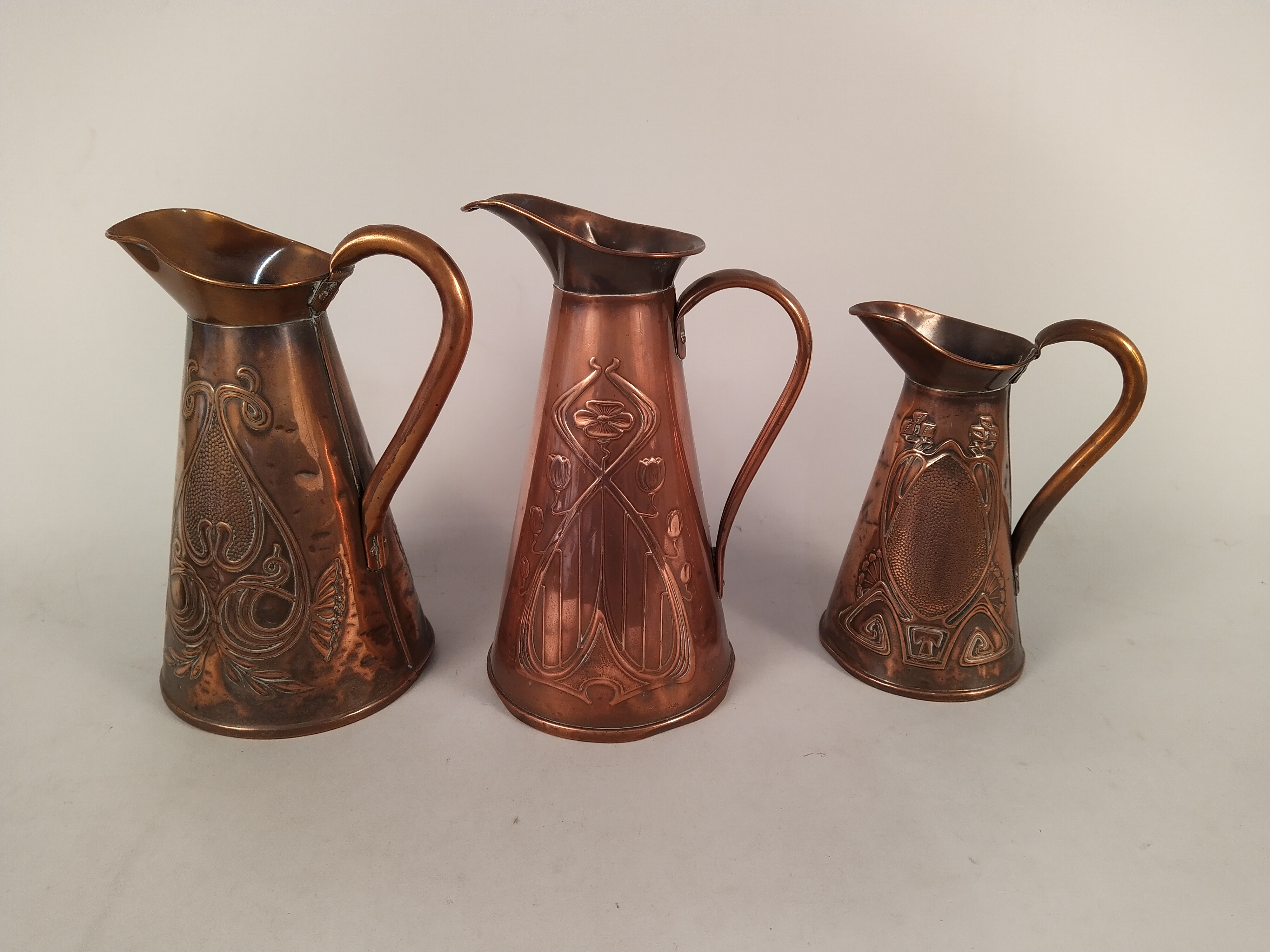 Three decorative Art Nouveau period copper jugs, the tallest marked JS&S (Joseph Sankey & Sons),