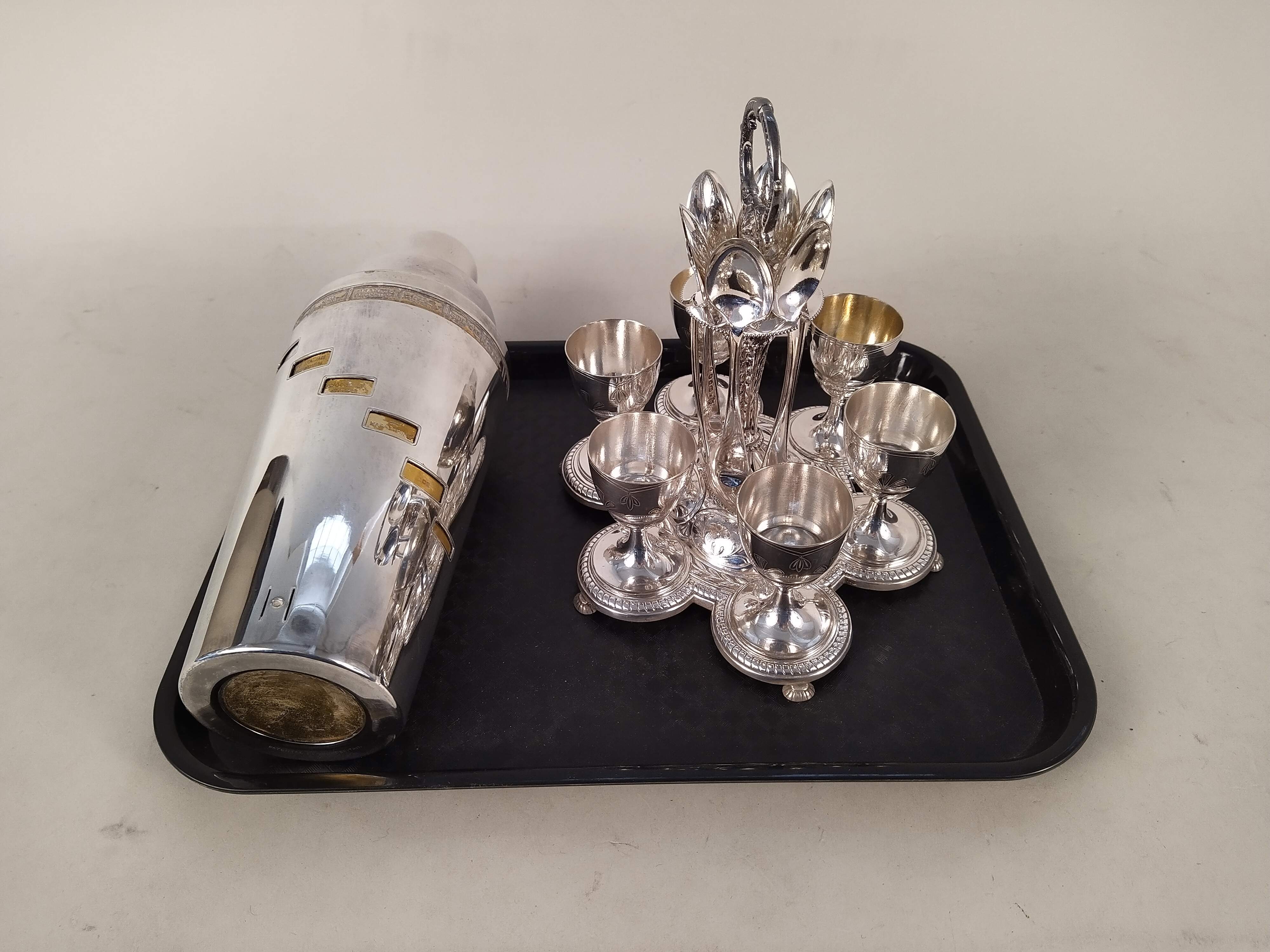 A white metal 'Dial a Drink' cocktail shaker plus an Elkington silver plate six setting egg cruet