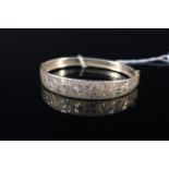 A 9ct gold bangle with matte effect finish and engraved foliate decoration, weight approx 9.