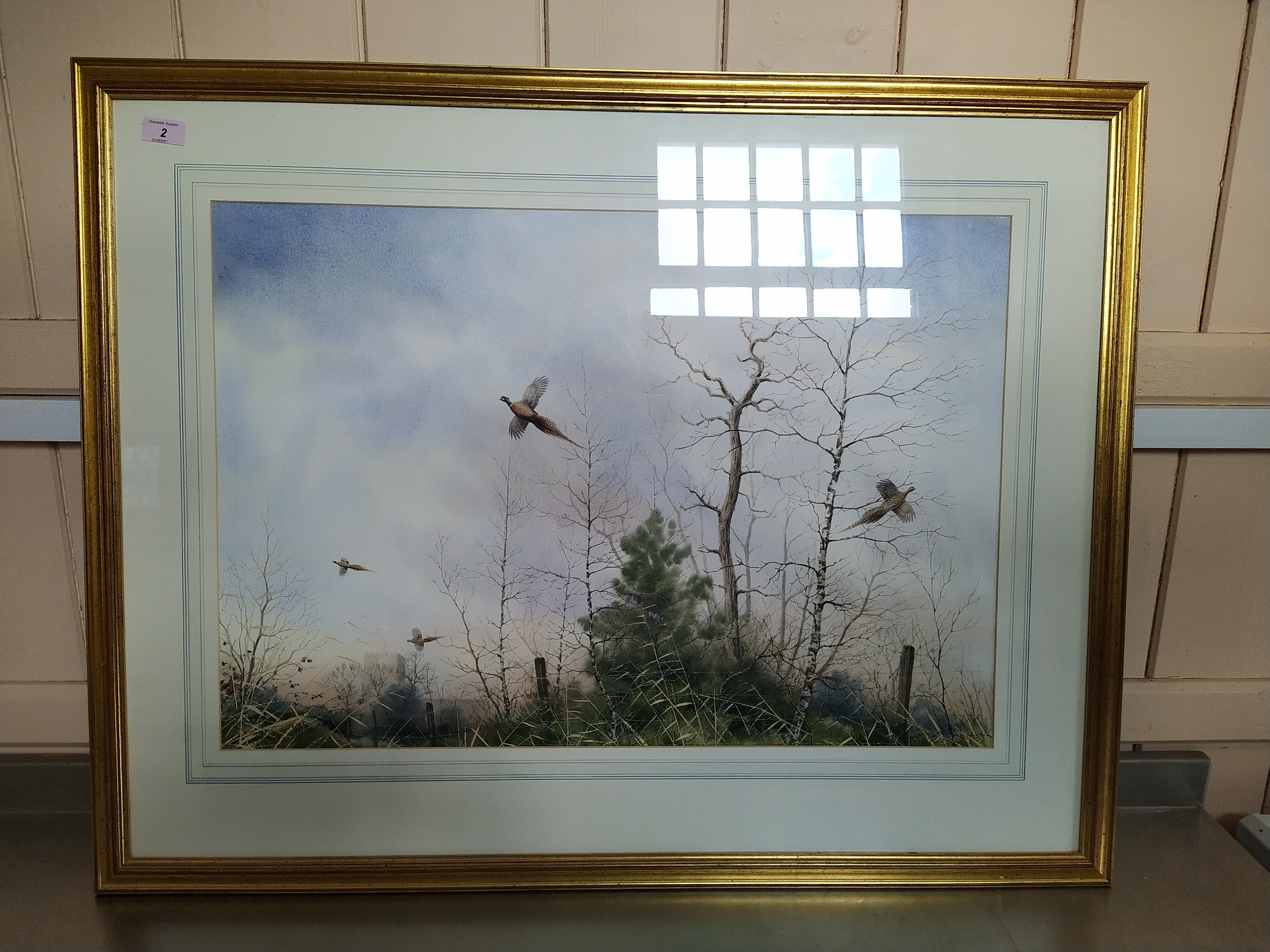 A framed unsigned watercolour of pheasants in flight in winter,