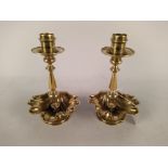 A pair of Arts and Crafts brass candlesticks by Benham & Froud with wide shell shaped drip trays on