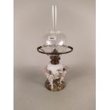 A late 19th Century Schierholz porcelain oil lamp of three cupids supporting basket moulded
