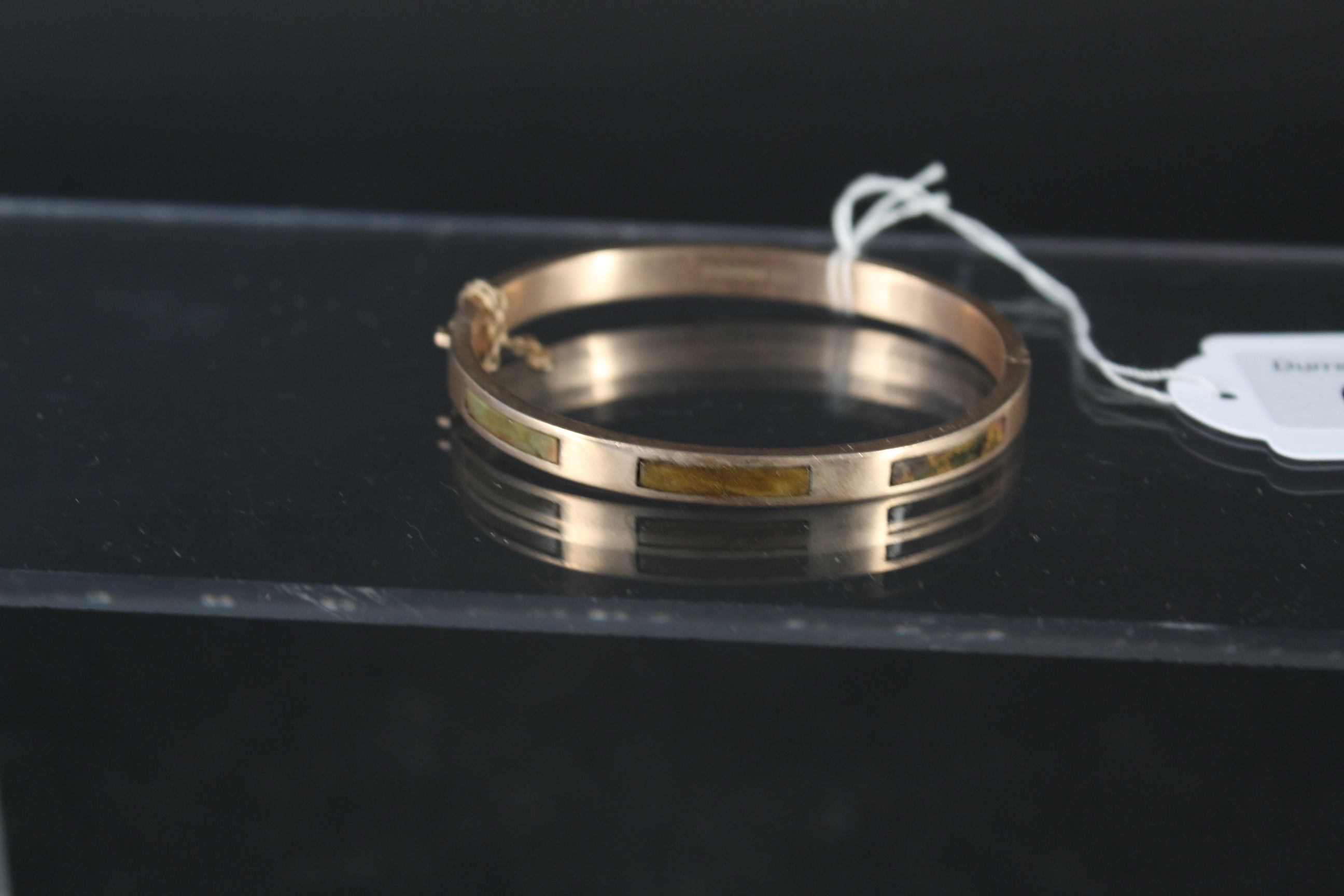 A 9ct gold bangle set with rectangular hardstone panels (as found),