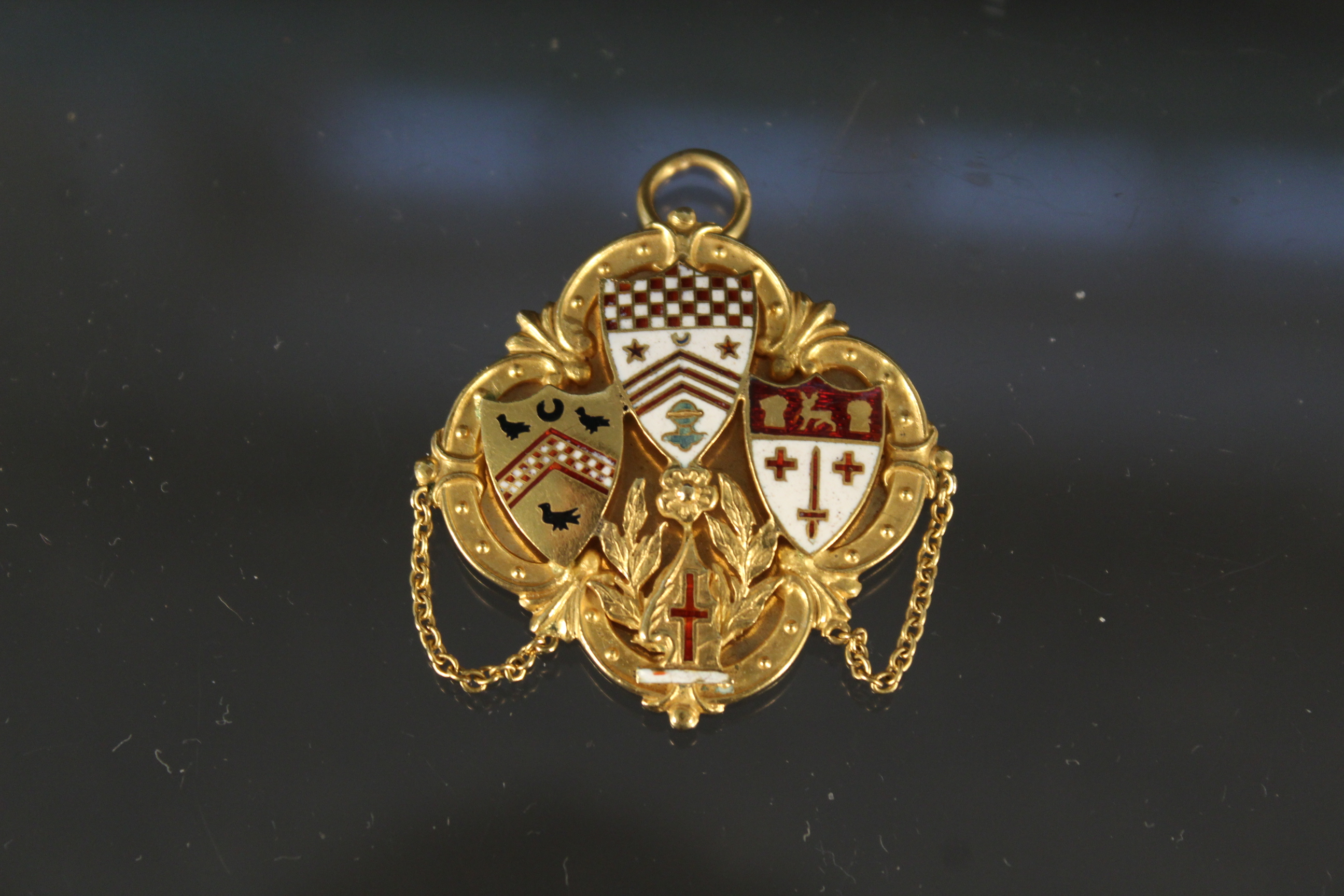 An 18ct gold pendant with enamelled crest decoration, weight approx 10.