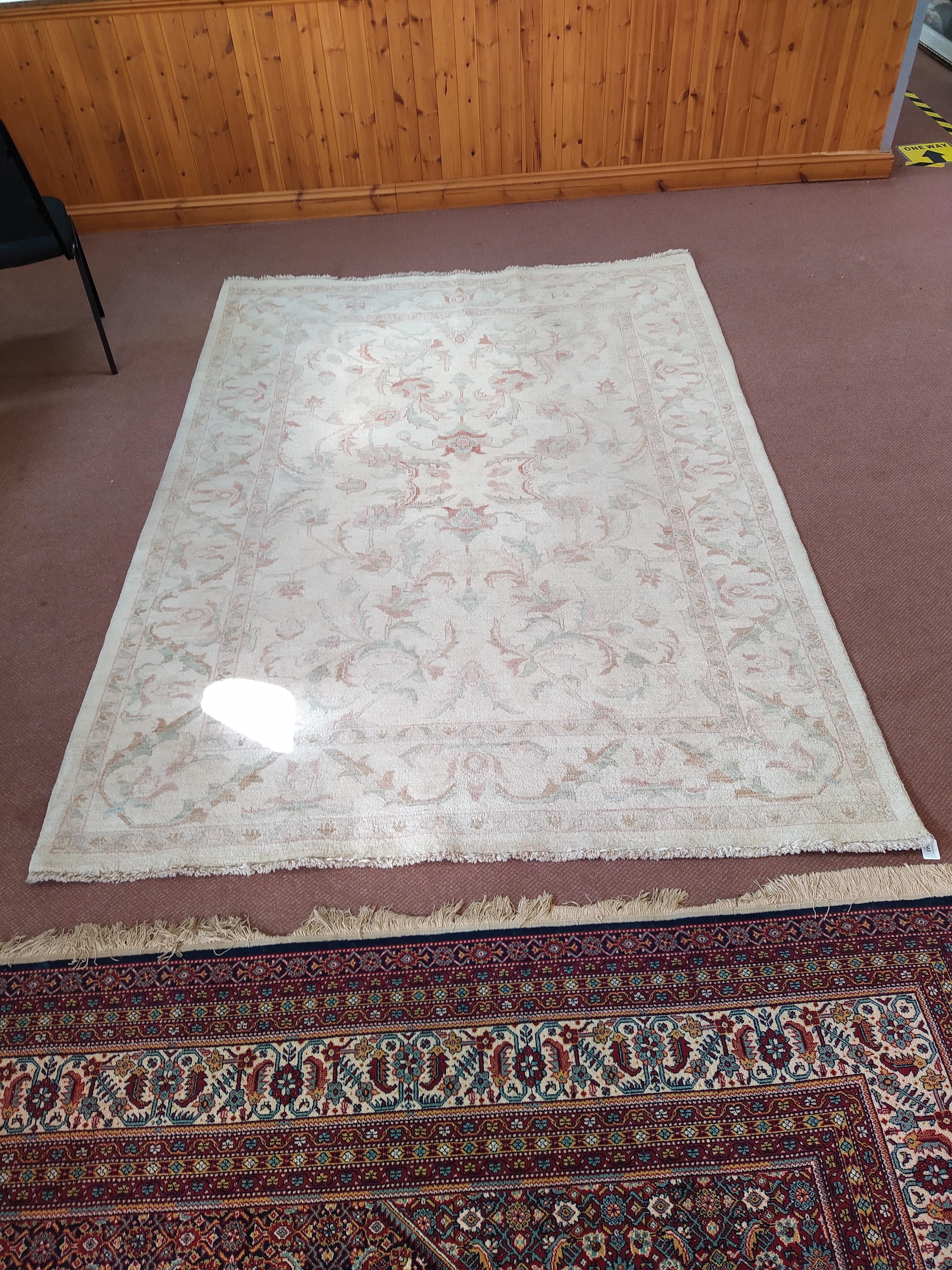 A wool rug with pale floral patterns against a beige ground,