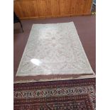 A wool rug with pale floral patterns against a beige ground,