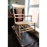 An Edwardian beech rocking chair with spindle back and canework seat