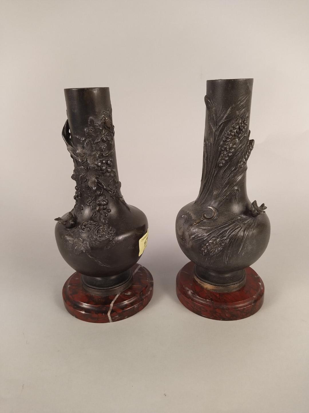 A pair of late 19th Century spelter vases on marble bases with raised decoration emblematic of