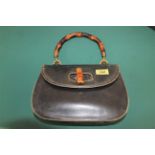 A vintage black Gucci bamboo handbag with an assortment of various other handbags,