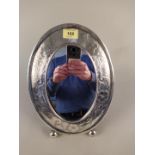 An oval sterling silver Deco style mirror with flower decorated border,