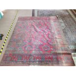 A machine made oriental style rug with stylised floral patterns on a dark red ground,