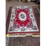 A machine made oriental style carpet with cream border and central medallion on a red ground plus a
